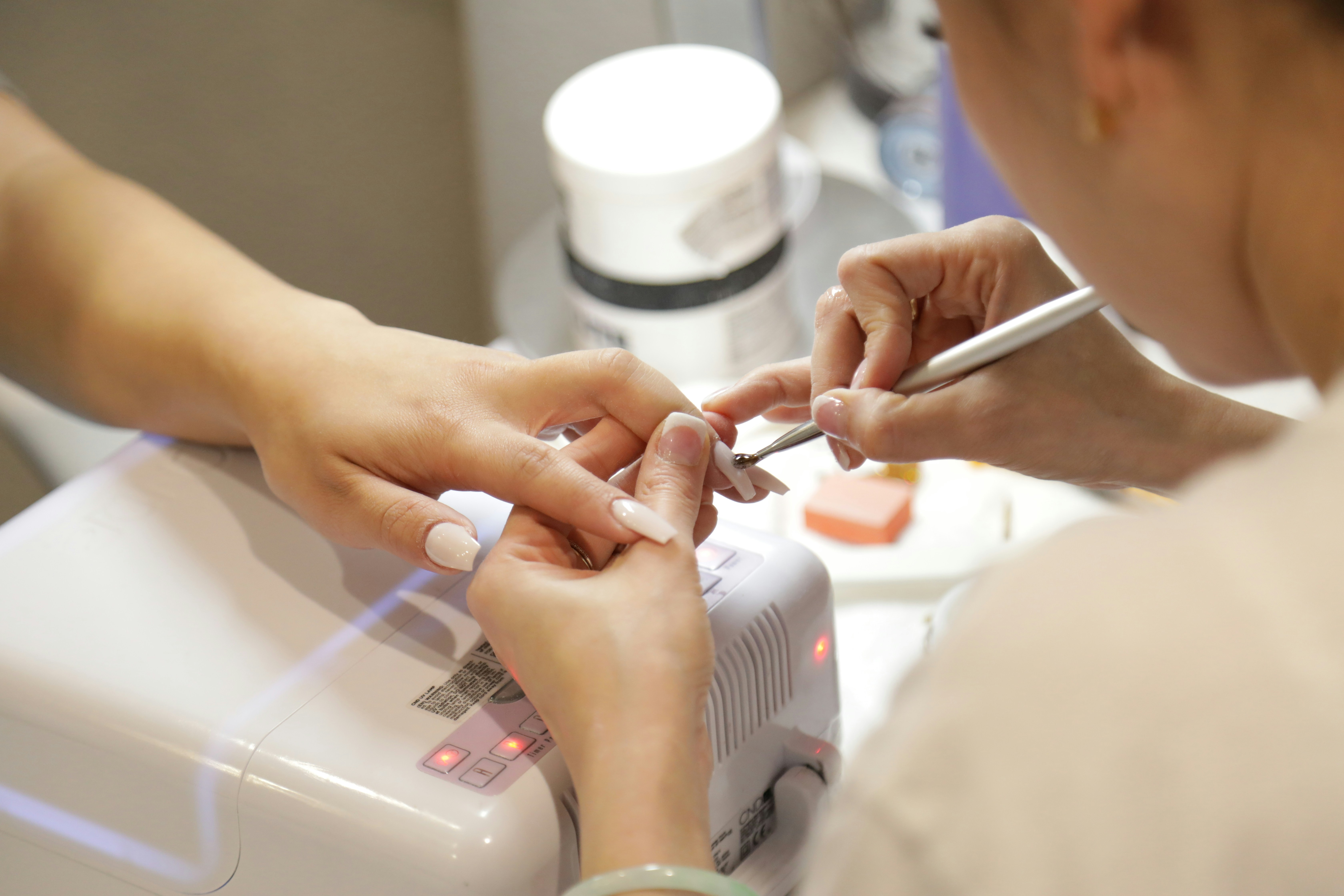 Nail technician at Luxe Nails applying acrylic set